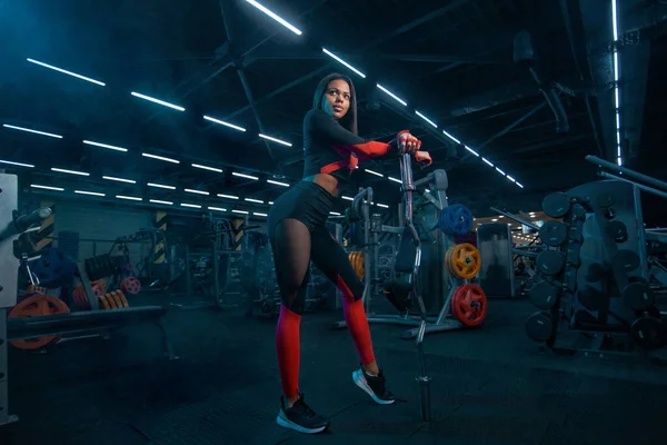 Musclé jeune fitness femme sportive séance d'entraînement avec haltère dans la salle de fitness. — Photo