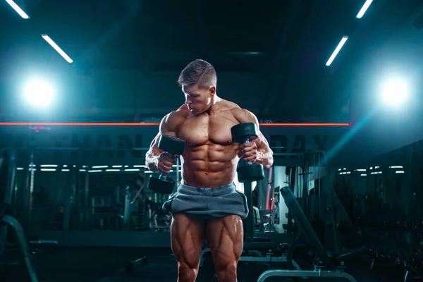 Bodybuilder Athlet Mann, der Muskeln in der Turnhalle mit Hanteln aufpumpt. Brutaler muskulöser Typ beim Fitnesstraining. Bodybuilding-Konzept. — Stockfoto