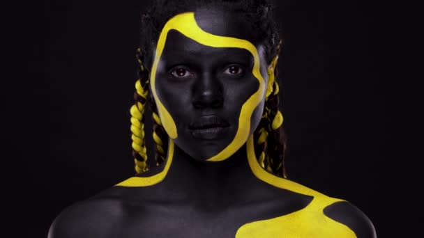 Obličej. Žena s černou a žlutou barvou na tělo. Mladá africká dívka s barevným nátěrem. Úžasný afro americký model se žlutým make-upem. Úzká tvář. — Stock video