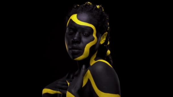 Искусство лица. Танцующая женщина с черно-желтой краской для тела. Молодая африканская девушка с красочной бодикраской. Удивительная афро-американская модель с желтым макияжем. Крупный план. — стоковое видео