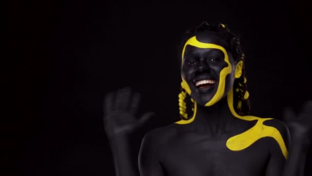 Искусство лица. Женщина с черно-желтой краской для тела. Молодая африканская девушка с красочной бодикраской. Удивительная афроамериканская модель с желтым макияжем. — стоковое видео