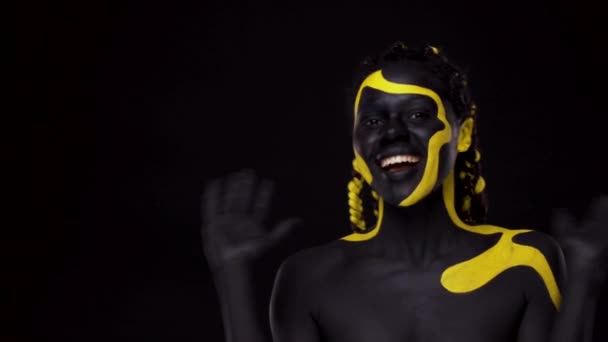 Cara de arte. Mujer con pintura corporal negra y amarilla. Chica africana joven con colorido bodypaint. Un increíble modelo afro-americano con maquillaje amarillo. — Vídeo de stock