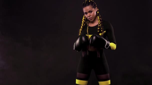 Boxing sport concept. Woman with yellow braids on black background. Girl sportsman muay thai boxer fighting in gloves in gym. — Stock Video