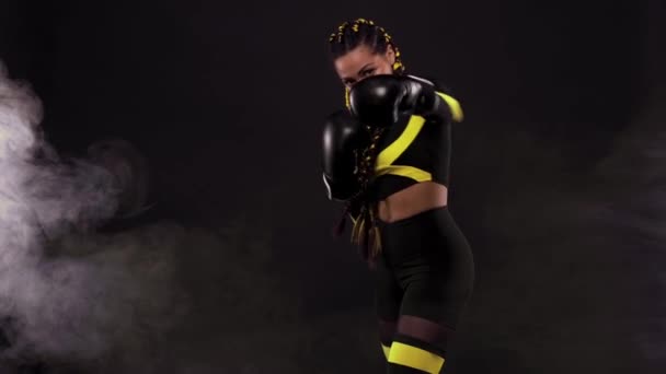 Concepto de boxeo deportivo. Mujer con trenzas amarillas sobre fondo negro. Chica deportista muay tailandés boxeador luchando en guantes en el gimnasio. — Vídeos de Stock