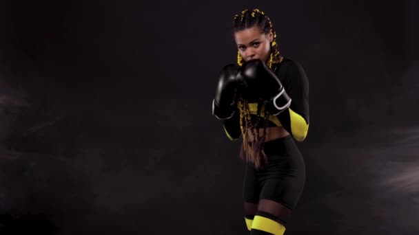 Boxing sport concept. Woman with yellow braids on black background. Girl sportsman muay thai boxer fighting in gloves in gym. — Stock Video