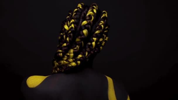 Obličej. Žena s černou a žlutou barvou na tělo. Mladá africká dívka s barevným nátěrem. Úžasný afro americký model se žlutým make-upem. — Stock video
