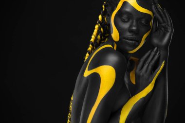 Yellow and black body paint. Woman with face art. Young girl with colorful bodypaint. An amazing afro american model with makeup. clipart