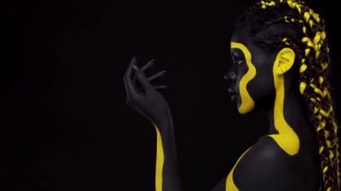 Yüz sanatı. Siyah ve sarı vücut boyalı bir kadın. Renkli vücut boyalı Afrikalı genç bir kız. Sarı makyajlı harika bir Afro-Amerikan modeli..