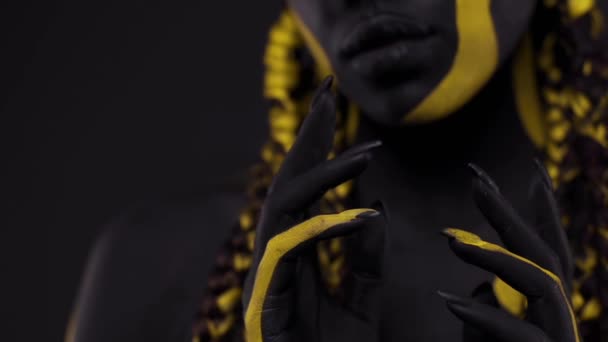 Cara de arte. Mujer con pintura corporal negra y amarilla. Chica africana joven con colorido bodypaint. Un increíble modelo afro-americano con maquillaje amarillo. — Vídeo de stock