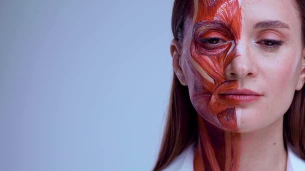 Jonge vrouw met half gezicht met spierstructuur onder de huid. Model voor medische training op een lichte achtergrond. close-up video van gezicht menselijke anantomie. — Stockvideo