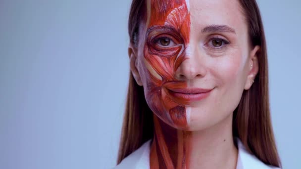 Wstrzyknięcie botoksu w twarz. Młoda kobieta z połową twarzy ze strukturą mięśni pod skórą. Model do szkolenia medycznego na lekkim tle. Zbliżenie wideo twarzy ludzkiej ananantomii. — Wideo stockowe