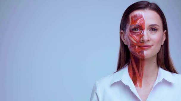 Jeune femme avec la moitié du visage avec la structure musculaire sous la peau pointant vers la gauche sur l'espace de copie.. Modèle pour la formation médicale sur un fond clair. Gros plan vidéo de l'anantomie humaine visage. — Video