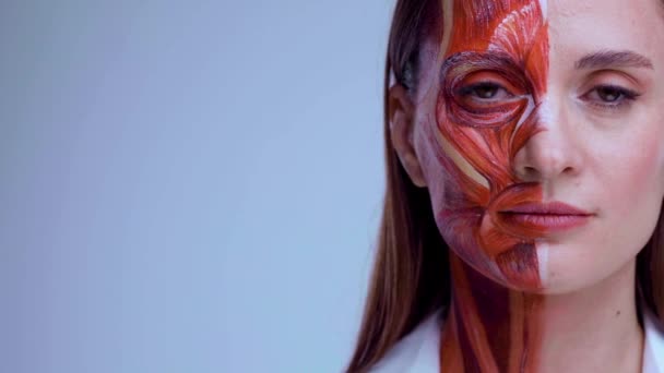 Junge Frau mit halbem Gesicht und Muskelstruktur unter der Haut. Modell für die medizinische Ausbildung auf hellem Hintergrund. Nahaufnahme Video von Gesicht menschliche Anantomie. — Stockvideo