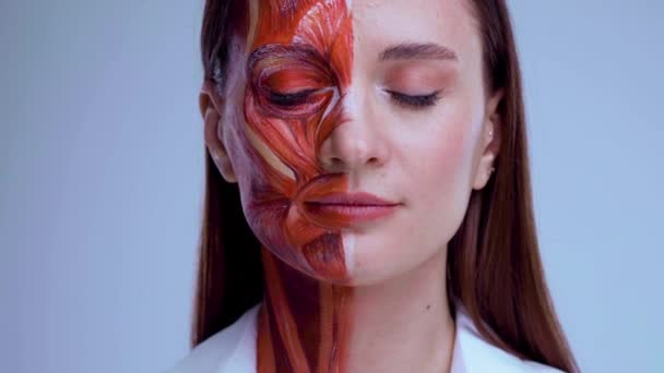 Jonge vrouw met half gezicht met spierstructuur onder de huid. Model voor medische training op een lichte achtergrond. close-up video van gezicht menselijke anantomie. — Stockvideo
