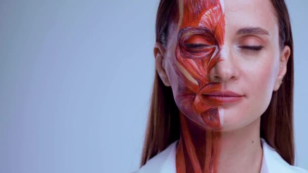Косметическая инъекция в лицо. Молодая женщина с половиной лица со структурой мышц под кожей. Модель для медицинской подготовки на светлом фоне. Закрыть видео анатомии лица человека. Стоковый Видеоролик