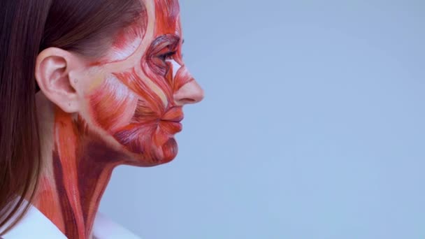 Косметическая инъекция в лицо. Молодая женщина с половиной лица со структурой мышц под кожей. Модель для медицинской подготовки на светлом фоне. Закрыть видео анатомии лица человека. Лицензионные Стоковые Видео