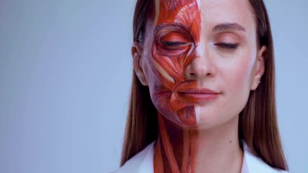 Косметическая инъекция в лицо. Молодая женщина с половиной лица со структурой мышц под кожей. Модель для медицинской подготовки на светлом фоне. Закрыть видео анатомии лица человека. Стоковый Видеоролик