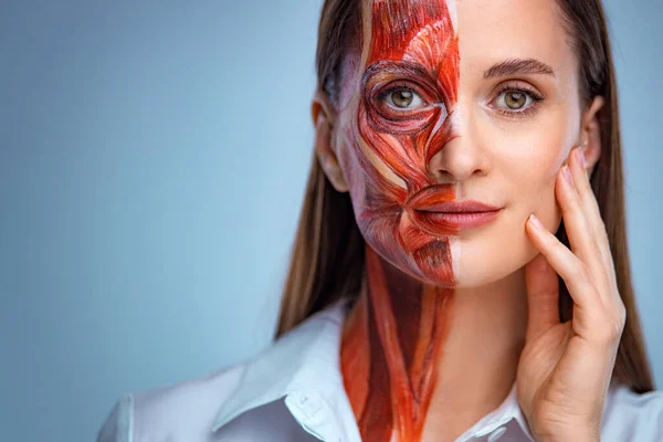 皮膚の下の筋肉構造を持つ顔の半分を持つ若い女性.軽い背景で医療訓練のためのモデル。顔のビデオを閉じます人間の解剖学. — ストック写真