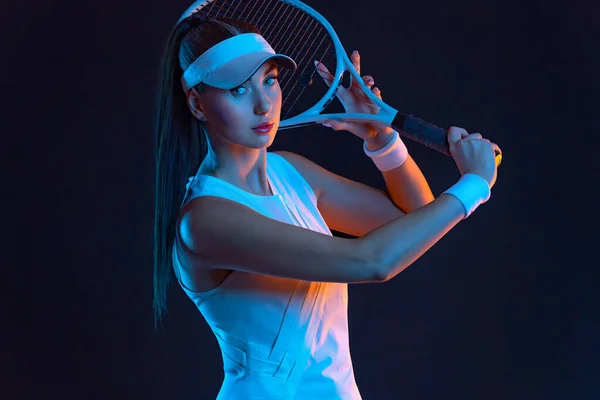 Beyaz kostümlü bir tenisçi. Siyah arka planda tek başına oynayan kadın sporcu. — Stok fotoğraf