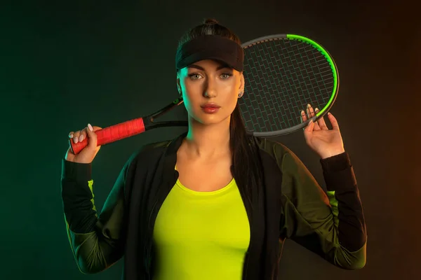 Joueur de tennis avec raquette en vêtements de sport. Athlète femme jouant fond sombre. — Photo