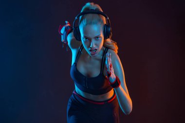 Koşucu konsepti. Hızlı koşu. Siyah arka planda koşan güçlü atletik kadın spor kıyafetlerini giyiyor. Spor ve spor motivasyonu.