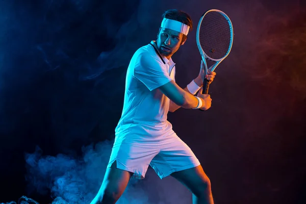 Παίκτης τένις με ρακέτα σε λευκό t-shirt. Αθλητής που παίζει σε σκοτεινό φόντο. — Φωτογραφία Αρχείου