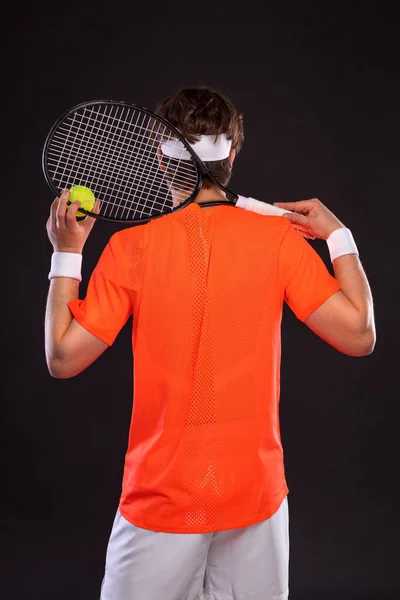 Tennisspelare med racket i orange t-shirt. Man idrottsman spela isolerad på svart bakgrund. — Stockfoto