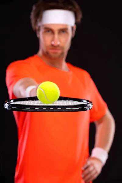 Jugador de tenis con raqueta en camiseta naranja. Hombre atleta jugando aislado sobre fondo negro. — Foto de Stock