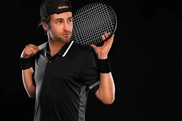 Jugador de tenis con raqueta en camiseta negra. Hombre atleta jugando aislado sobre fondo oscuro. — Foto de Stock