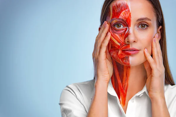 Cosmetology concept. Young woman with half of face with muscles structure under skin. Model for medical training on a light background. Close up portrait of face human anantomy. — Zdjęcie stockowe