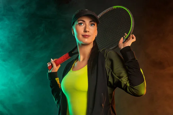 Joueur de tennis avec raquette en vêtements de sport. Athlète femme jouant fond sombre. — Photo