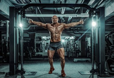 Vücut geliştirme sporcusu spor salonunda antrenman yapıyor. Antrenman aleti olan kaslı bir adam. Spor ve spor motivasyonu. Vücut geliştirme ile bireysel spor eğlencesi.
