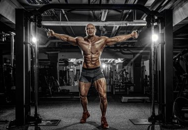 Vücut geliştirme sporcusu spor salonunda antrenman yapıyor. Antrenman aleti olan kaslı bir adam. Spor ve spor motivasyonu. Vücut geliştirme ile bireysel spor eğlencesi.