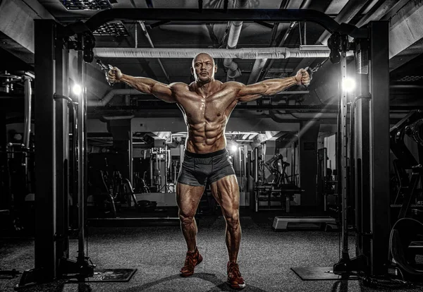 Bodybuilder-Athlet trainiert im Fitnessstudio. Sportlicher, muskulöser Typ mit Trainingsgerät. Sport- und Fitness-Motivation. Individuelle Sportgestaltung mit Bodybuilding. — Stockfoto