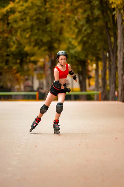 Patinaje niña en el parque patinaje sobre patines en línea. Mujer joven caucásica en actividades al aire libre. — Foto de Stock