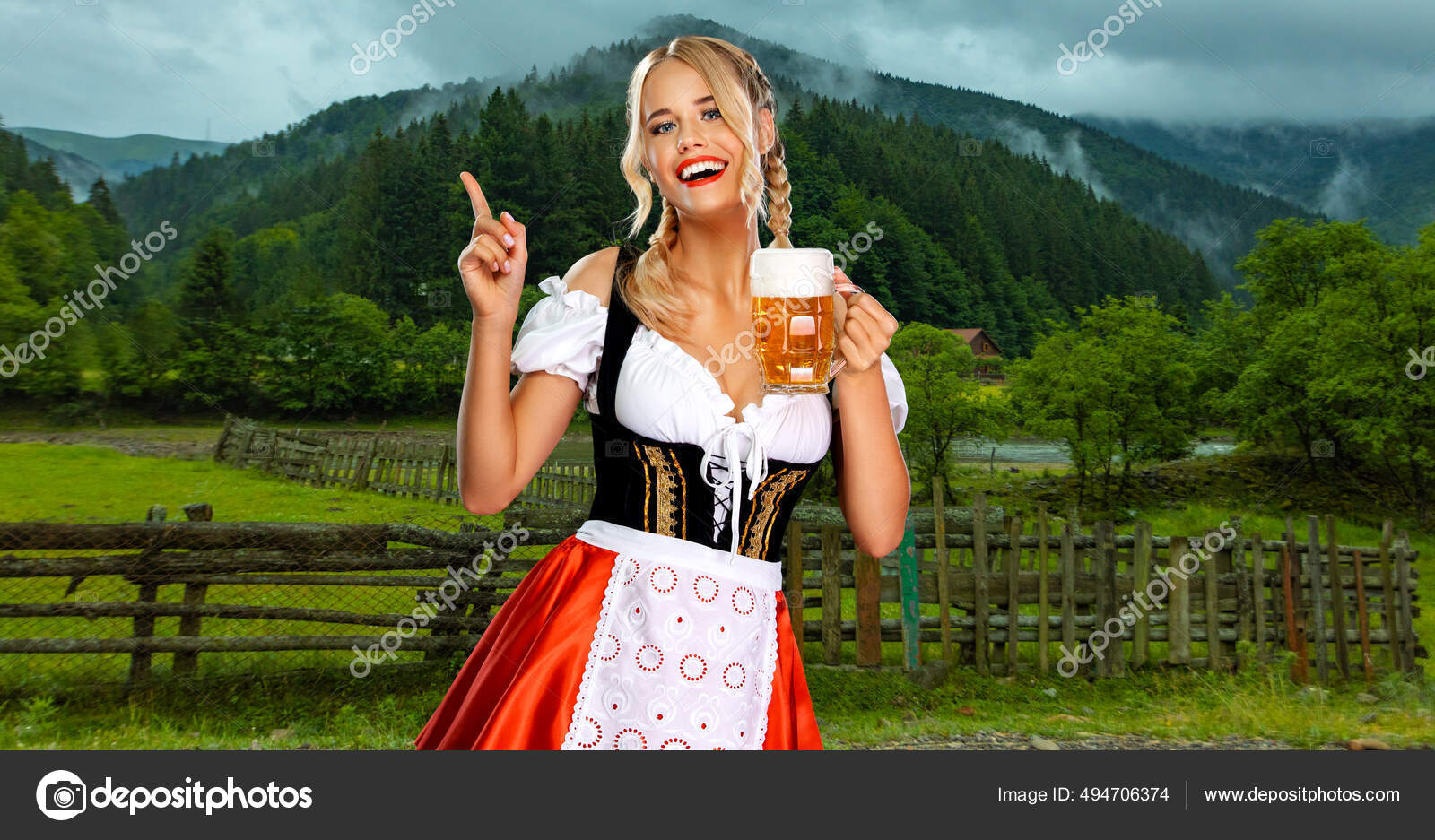 Oktoberfest girl waitress with beer. Woman wearing a traditional Bavarian  or german dirndl on octoberfest, serving big mugs with drink on mountains  background. Woman pointing to looking up. Stock Photo by ©MikeOrlov
