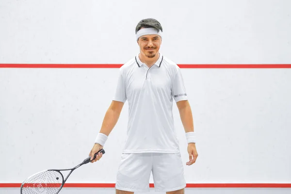 Un joueur de squash sur un terrain de squash avec la raquette. Vêtements de sport blancs. — Photo