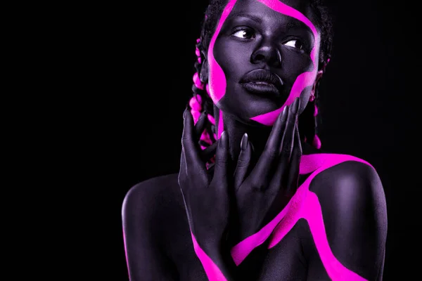 Neonfärger. Rosa och svart kroppsfärg. Kvinna med ansiktskonst. Ung flicka med färgglad kroppsfärg. En fantastisk afro amerikansk modell med makeup. — Stockfoto