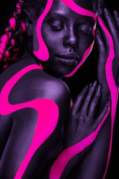 Neonowe kolory. Różowa i czarna farba do ciała. Kobieta ze sztuką twarzy. Młoda dziewczyna z kolorowym farbą do ciała. Niesamowity afro amerykański model z makijażem. — Zdjęcie stockowe