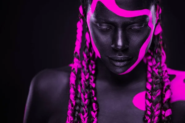 Неоновые цвета. Розовая и черная краска для тела. Женщина с лицом. Молодая девушка с красочной бодикраской. Удивительная африканская модель с макияжем. — стоковое фото