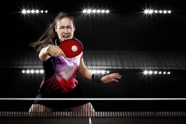Young sports woman tennis-player in play on black background. Action shot. clipart