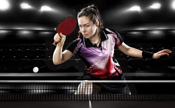 Giovane ragazza abbastanza sportiva giocare a ping pong su sfondo nero. Azione svolta . — Foto Stock