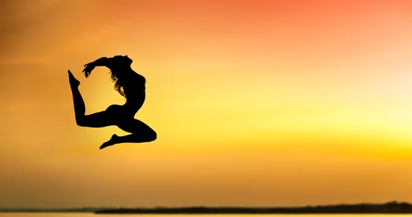 Silueta de una joven saltando al atardecer — Foto de Stock