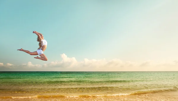 Mulher ajuste bonito pulando na praia perto do oceano — Fotografia de Stock