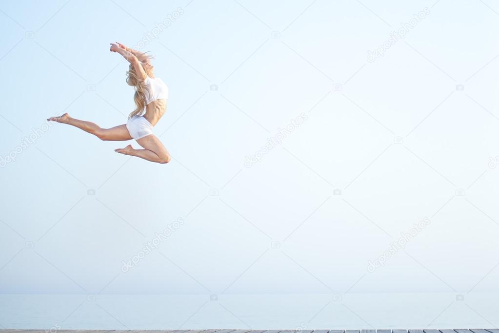 Beautiful fit woman  jumping at the beach near ocean