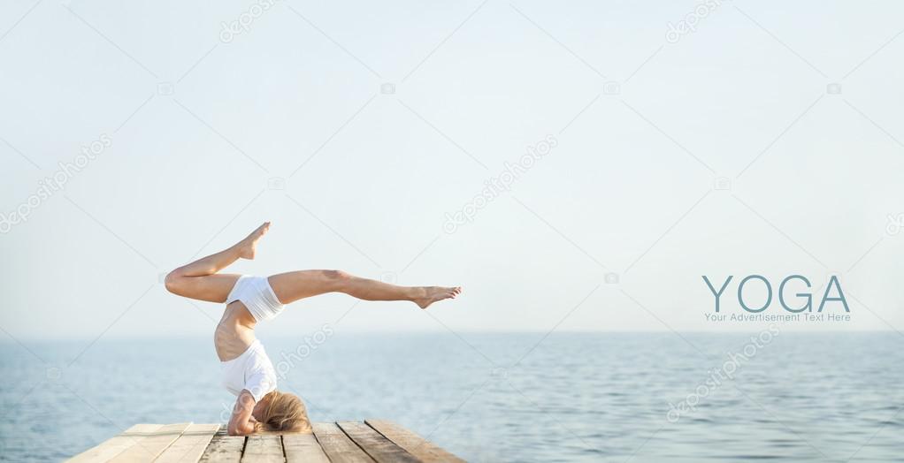 Beautiful positiveblond girl practicing yoga at seashore and meditating 