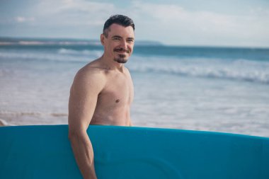 Okyanusta sörf yapmayı öğrenen bir sörfçü. İlk sörf dersi. Amatör sörfçü. Sörf eğitimi. Sosyal medyada sörf okulu reklamı için fotoğraf.