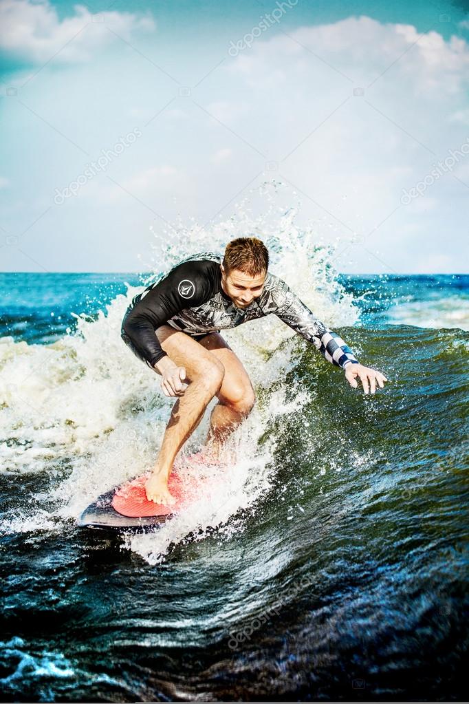 Surfing at blue sea. Young man touched wave on surfboard.