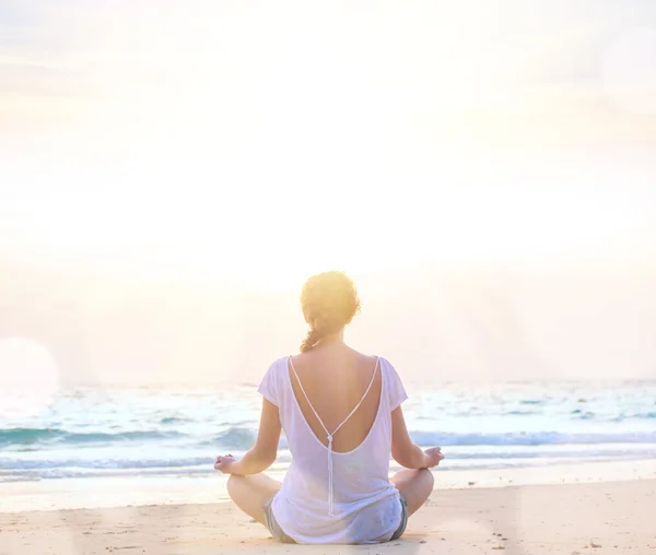 Vrouw het beoefenen van yoga bij sunrise beach — Stockfoto
