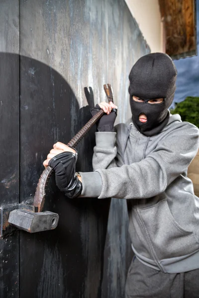 Man in masker breken van een hangslot metalen deur open — Stockfoto